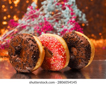 Stack of flattering tasty doughnuts on reflective surface and soft bokeh background. Fine bakery product and delicious dessert. Good for food blogs and industry.