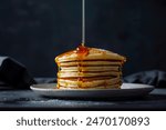 Stack of fluffy pancakes with maple syrup cascading down the sides.