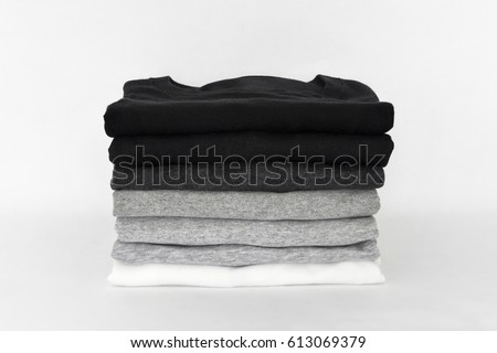 stack of folded black, grey and white color (monochrome) t-shirt on white background