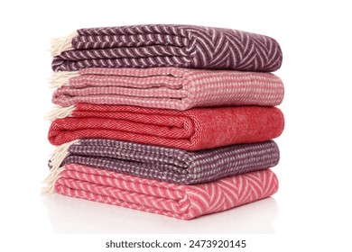 A stack of folded blankets lying on top of each other. On a white background