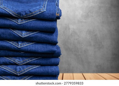 Stack of folded blue denim jeans on wooden table with copy space