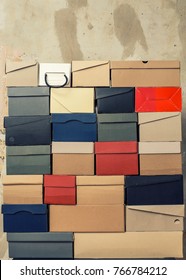 A Stack Of Folded Cardboard Boxes From Under The Shoes Stands Against The Background Of A Shabby Wall.