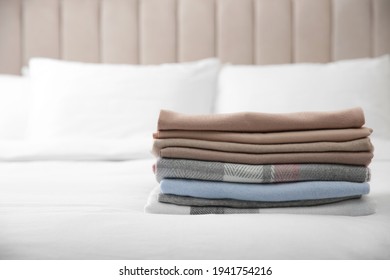 Stack Of Folded Cashmere Clothes On Bed
