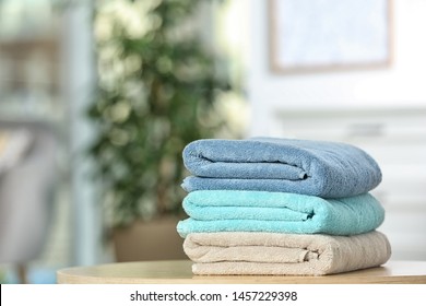 Stack of folded clean soft towels on table indoors. Space for text