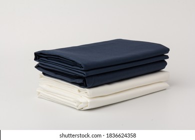 Stack Of Folded Clean White And Blue Bed Sheets And Pillowcases On White; Background; Closeup.