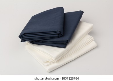 Stack Of Folded Clean White And Blue Bed Sheets And Pillowcases On White; Background; Closeup.