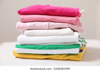 Stack of folded clothes on table against beige background