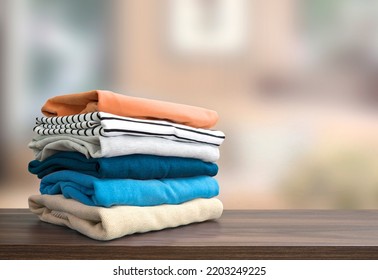 Stack of folded clothing, autumn colors stacked sweaters.Heap of clothes.Laundry,household on wooden table empty space.
