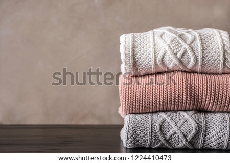 Stack of folded knitted sweaters on table. Space for text