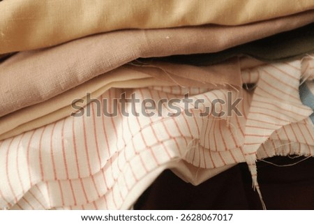 Stack of folded linen fabric in a sewing atelier. Soft colors canvas, textured textile, woven linen fabric. Aesthetic textile collection in a dressmaker workshop. 