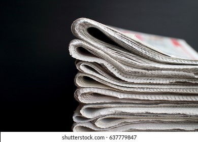 Stapel gefalteter Zeitungen auf schwarzem Hintergrund mit Kopienraum