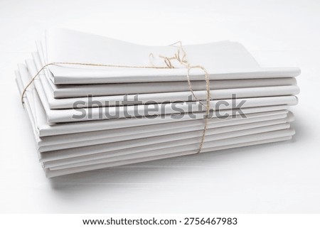 Stack of folded newspapers on white wooden table, closeup