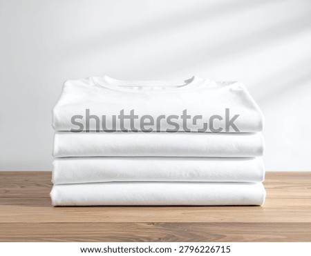 Stack of folded plain white t-shirts on a wooden surface