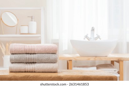 Stack of folded soft bath towels on table against blurred bathroom interior background with copy space. NO AI USED