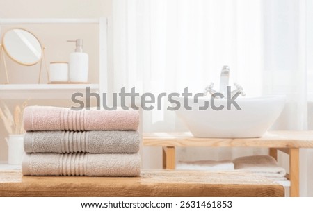 Stack of folded soft bath towels on table against blurred bathroom interior background with copy space. NO AI USED