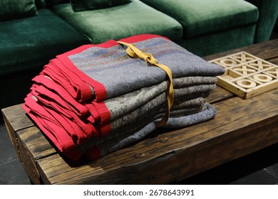 Stack of Folded Warm Blankets Tied with Rope on Wooden Table