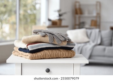Stack of folded winter clothes on table in room, closeup
