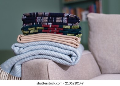 Stack of folded woolen checked blankets on the sofa in living room, autumn and winter concept
