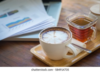 stack of folders and documents on office desk with coffee and laptop