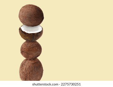 Stack of fresh coconuts on beige background. Space for text