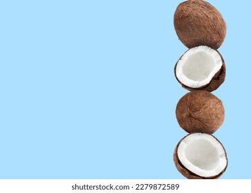 Stack of fresh coconuts on pale light blue background. Space for text
