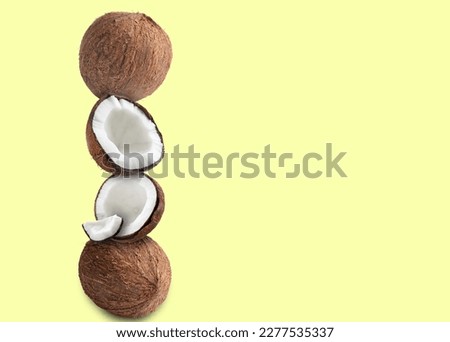 Stack of fresh coconuts on pale light yellow background. Space for text