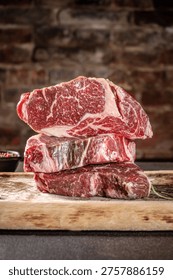Stack of fresh raw marbled beef steaks on rustic wooden board with rich texture and natural lighting highlighting premium quality meat.