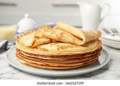 Stack of fresh thin pancakes on white marble table