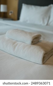 Stack of fresh white bath towels neatly placed on a bed linen. Coziness and clean concept