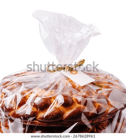 A stack of freshly baked bread is neatly wrapped in clear plastic, tied with a bow. The aroma of warm bread fills the air, inviting customers to enjoy this delicious treat.
