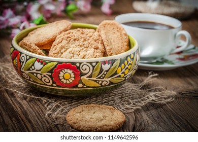Stack of freshly baked oat biscuits in a bowl standing on a wooden table.
