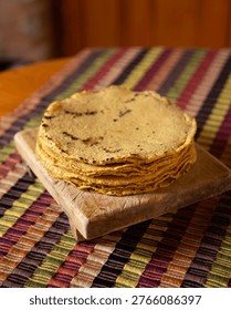 Stack of freshly made corn tortillas on a handmade textile fabric from Chiapas, Mexico.