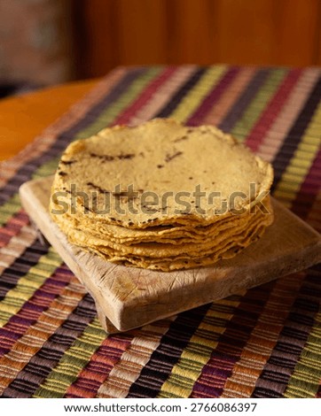 Stack of freshly made corn tortillas on a handmade textile fabric from Chiapas, Mexico.