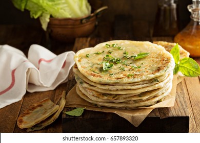 Stack of fried green onion pancakes on a wooden board