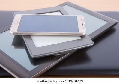 Stack Of Gadgets On A Desk - Notebook, Tablet, Ebook Reader And A Smatphone