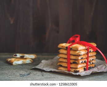 A stack of gift cookies wrapped with a red festive ribbon on a wooden background. Copy space