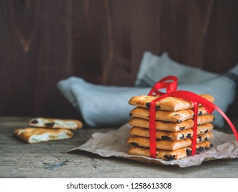 A stack of gift cookies wrapped with a red festive ribbon on a wooden background. Copy space