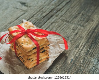 A stack of gift cookies wrapped with a red festive ribbon on a wooden background. Copy space