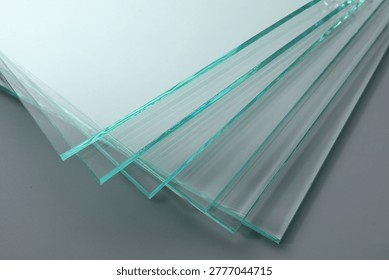 Stack of glass sheets on grey background, closeup