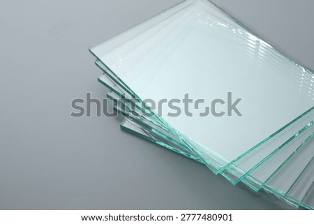 Stack of glass sheets on grey background, closeup. Space for text