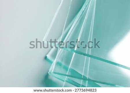 Stack of glass sheets on light background, closeup. Space for text
