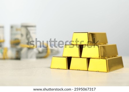 Stack of gold bars on light table against grey background, closeup. Space for text