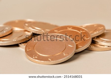 Stack of gold casino chips with a subtle texture on a light brown surface. Gambling and betting concept and symbol