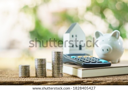 Stack gold coin with benefit from dividend and growth of value and house and calculator  and piggy bank put on the table in the backyard, Saving money buy home and Investment real estate concept.