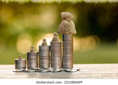 Stack gold coins and money bag put on the top with growing invest on the wood on sunlight in public park, Saving money and loan for business investment concept. - Shutterstock ID 2214383699