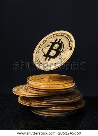 Stack of golden bitcoins with one flying token coin on black background. Creative cryptocurrency investment or blockchain digital concept. Stock Market, digital gold money and stock business.