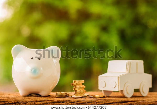 Stack golds coin of\
grow and piggy bank and car put on the old wooden in the public\
park, saving money for buying, or sold a new car for working\
capital management\
concept.