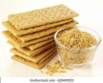 STACK OF GRAHAM CRACKERS WITH CRACKER CRUMBS IN BOWL