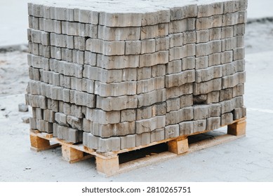 A stack of gray concrete blocks is placed on wooden pallets. This setup is commonly found at construction sites and materials supply locations.