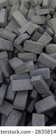 Stack of gray concrete paving blocks or bricks piled together. Used for road construction, sidewalk, and housing development in Indonesia. Building material and construction concept